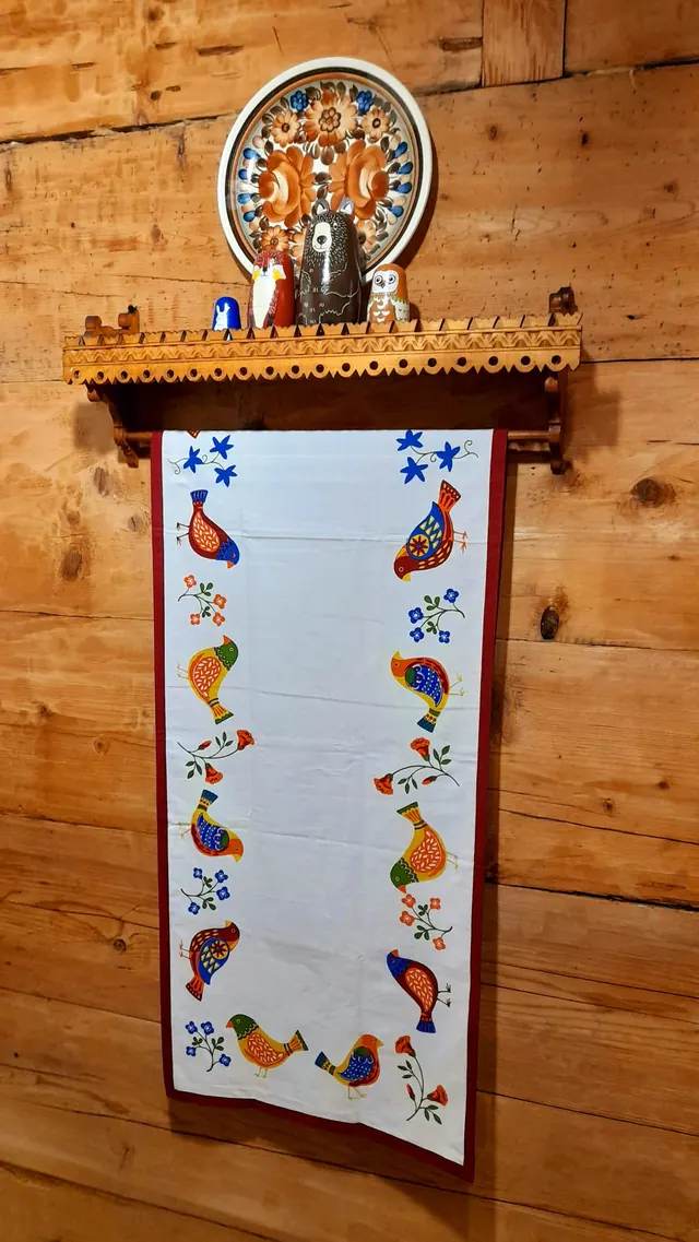 Haftowana makatka i ludowe ozdoby na ścianie z bali