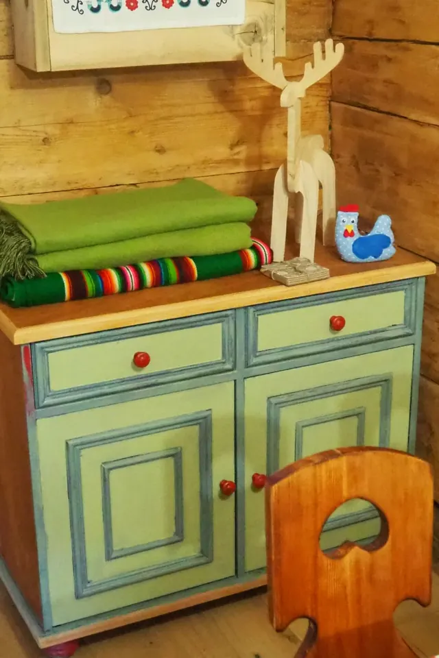 Ręcznie malowana komoda, koce i ludowe ozdoby